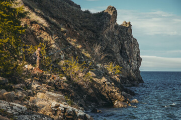 a man with a fishing rod stands on a rocky shore against the backdrop of rocks