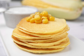 Tasty corn pancakes served on white table, closeup