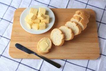 Cut baguette with fresh butter on checkered tablecloth