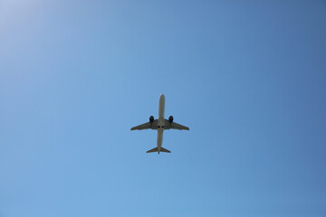 Modern white airplane flying in sky, bottom view
