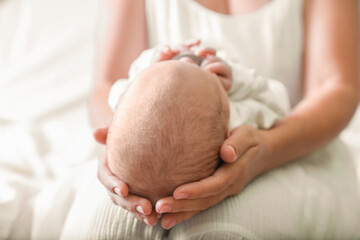 Mother holding newborn baby indoors, focus on head