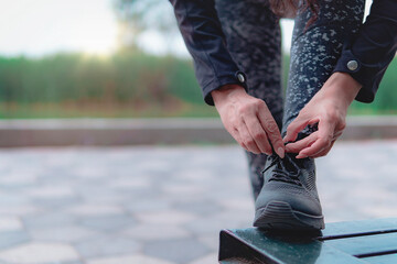 Close up of a woman tying shoelaces. Women's sneaker ready for outdoor running in the park