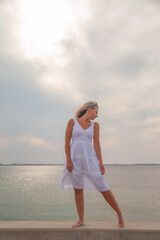 young happy woman in a white dress by the sea