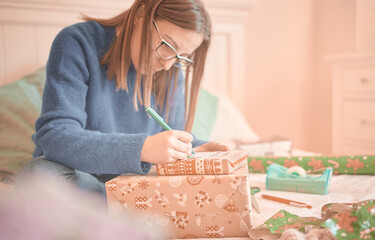 Obraz na płótnie Canvas Young woman writes a name on christmas presents wrapped with decorative paper for her children during the christmas holidays. Reyes Magos concept.