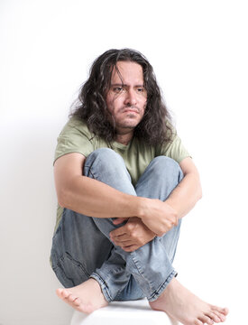 a disheveled man with a blank stare huddled and anguished