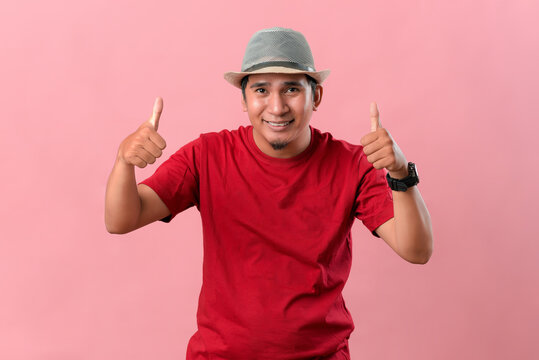 Asian man showing the thumbs up isolated on pink background.