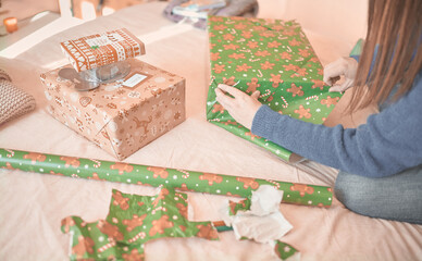 Obraz na płótnie Canvas Young woman's hands wrap christmas presents with decorative paper for her family during the christmas holidays.
