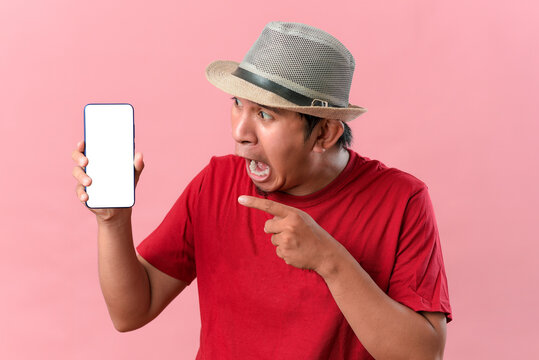Young Asian man showing a phone screen for copy space with funny gesture