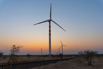 Obraz premium Pre dawn light in desert sky with Electrical power generating wind mills producing alterative eco friendly green energy for consumption by local people. Thar desert, Rajasthan, India.