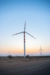 Pre dawn light in desert sky with Electrical power generating wind mills producing alterative eco...