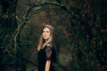 Beautiful Queen Wearing a Crown and a Black Lace Dress. Gorgeous dark princess standing alone in the forest 
