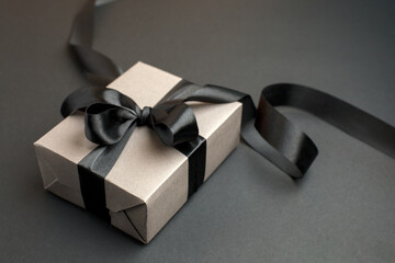 Craft gift box on a dark background, decorated with a textured bow, creating a romantic luxury atmosphere. For birthday, anniversary presents, gift post cards, banner, flyer, invitation, voucher - 548643532