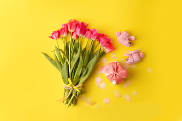Pair of small baby girl socks, bouquet of pink tulips and gift box on yellow background with copy space for your warm message, baby shower, first newborn party background, copy space