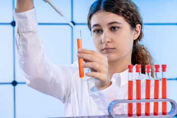 young adult female student in a science laboratory with chemical experiments fill test tubes with a...