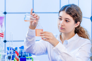 young adult female student examining a cell culture flask in the microbiological laboratory of the university