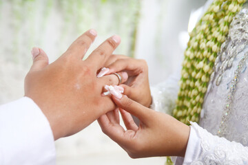 The bride puts the wedding ring on the groom's ring finger