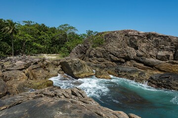 Fototapeta na wymiar Natural landscape in the Escape of Islands, Barra do Sahy, São Sebastião, Brazil. As Ilhas. Turquoise sea and waves hitting the rocks.