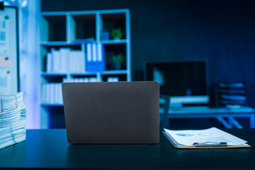 Laptop Computer in office workplace at night, overtime business object on the working desk.
