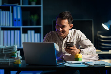 Overtime work concept, Handsome asian business man working late at night in office workplace.
