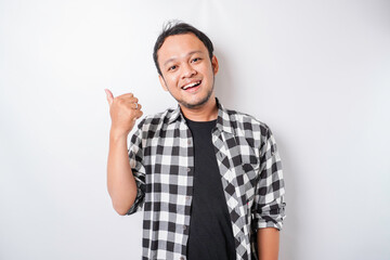 Excited Asian man wearing tartan shirt gives thumbs up hand gesture of approval, isolated by white background