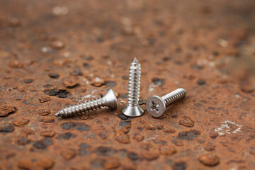 Tapping screws made of steel on steel rusty background, metal screw, iron screw, chrome screw, screws as a background, wood screw, concept industry. copy space for text.