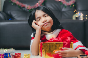 Girl wearing Santa Claus costume with a small christmas gift box and looking happy.