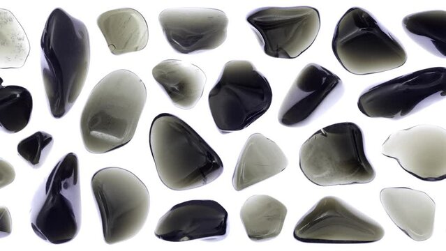 Obsidian jewel stones set texture on white light isolated background. Moving right seamless loop backdrop.