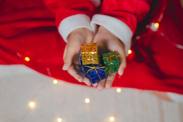 Children's hands holding small presents for Christmas and New Year.
