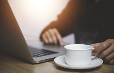 Man working in front of a laptop with hot coffee with smoke and steam