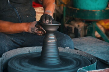 Midsection of professional potter making bowl in pottery workshop
