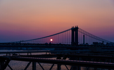Fototapeta na wymiar Rising sun through the ropes of the Manhattan bridge at dusk