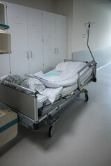 in a hospital corridor there is an empty patient bed