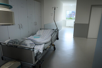 in a hospital corridor there is an empty patient bed