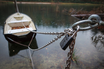 Rowing boats are secured with a chain and a padlock - obrazy, fototapety, plakaty