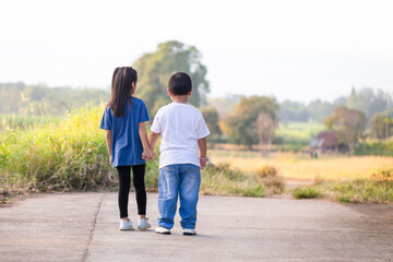 Happy children playing outdoors in park. Asian kids playing in garden, boy and girl holding hands