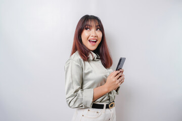 Fototapeta premium Photo of a thoughtful young woman holding her phone and looking aside; isolated on white color background