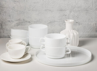 Different ceramic white dishes on a white table. Minimalism in serving.