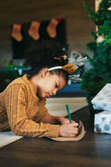 Christmas, celebrate and girl writing in a card, list or letter for holiday on the living room...