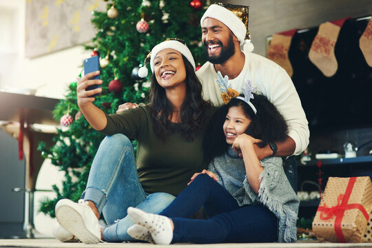 Selfie, family and christmas with a mother, father and daughter sitting for a photograph at home with a gift by a tree. Kids, fun and love with a girl, woman and man posing for a festive picture