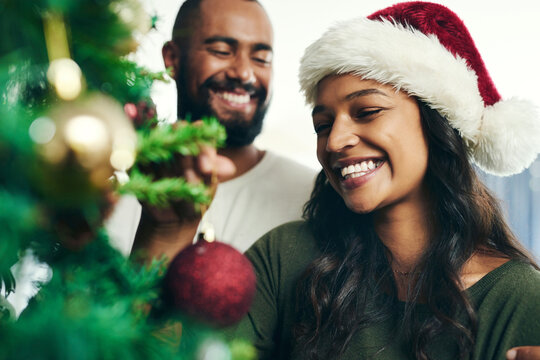 Christmas, tree and smile with a black couple decorating in the home together for the festive season. Love, celebration and holidays with a happy man and woman in a santa hat while bonding in a house