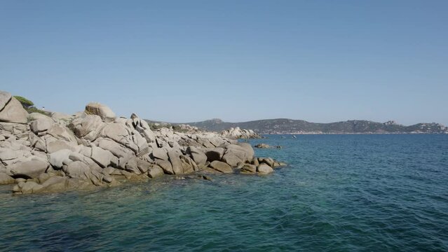 Southwest Corsica Island France, Tizzano Beach in Mediterranean Sea with breakwater rock formations on the shore, Aerial dolly flyover shot