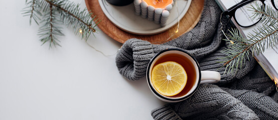Morning lemon tea, open book, warm sweater, candles and fir tree. Wellbeing, morning rituals, useful habit concept. Top view, copy space. Banner for design