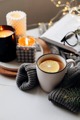 Cup with tea, warm sweater, candles, present gifts and fir tree. Winter home cozy concept - 548662586