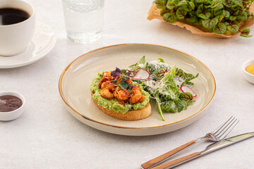 Portion of avocado toast with grilled shrimp and salad