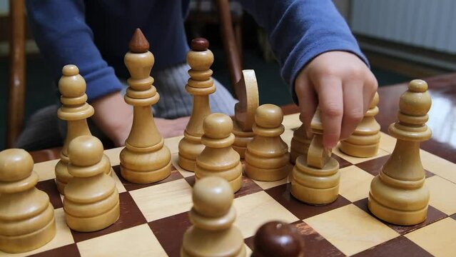 Little boy toddler is playing chess. Moves the knight piece on the chessboard. High quality close up FullHD footage