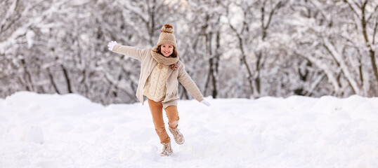 Happy excited little girl playing in winter park, kid running through snow with arms outstretched - Powered by Adobe