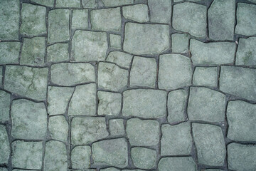 The texture of a stone walkway made of uneven bricks.