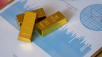 Small gold ingots on financial statistics document with charts and graphs - obrazy, fototapety, plakaty