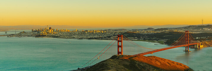 Wide angle view of San Francisco skyline and Golden Gate Bridge at sunset