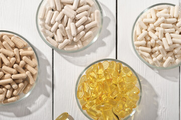 various supplement pills omega 3 and vitamins in petri dishes. healthcare support, top view, flat lay.